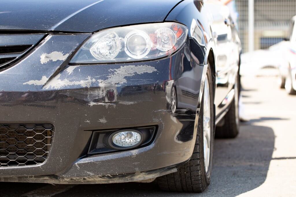 Die Frontstoßstange eines Autos mit deutlich sichtbaren Kratzern und Lackschäden, als automatisch gespeicherter Entwurf markiert